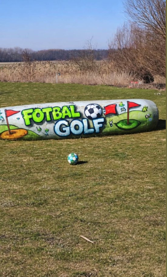 Lodička/člun s nápisem FOTBAL GOLF na trávníku